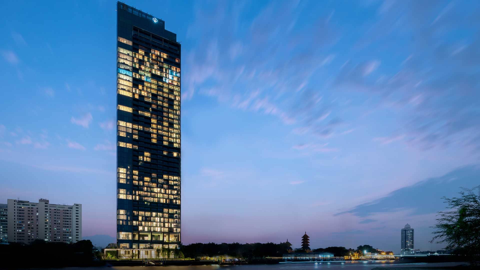 Banyan Tree Residences Riverside Bangkok tower beside the Chao Phraya River at dusk