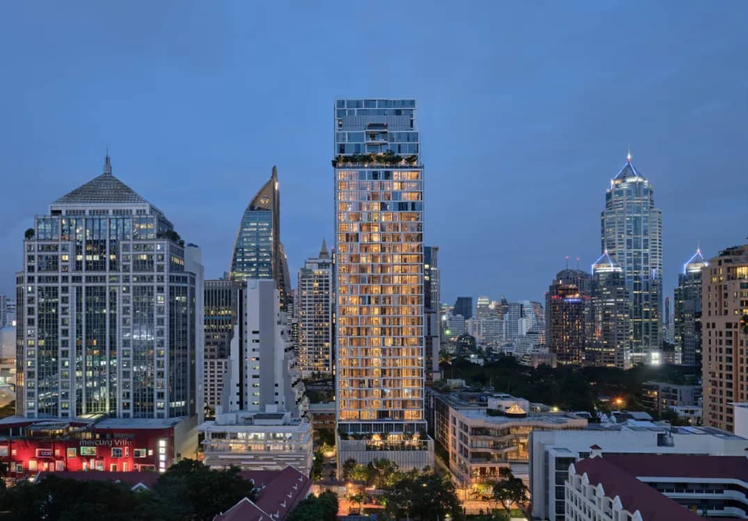 SCOPE Langsuan tower lit up at dusk above the Bangkok skyline