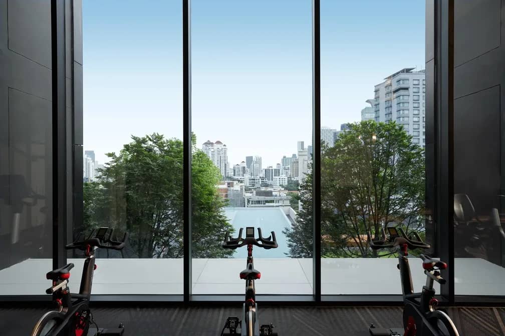 The Esse Sukhumvit 36 gym spin bikes facing the city