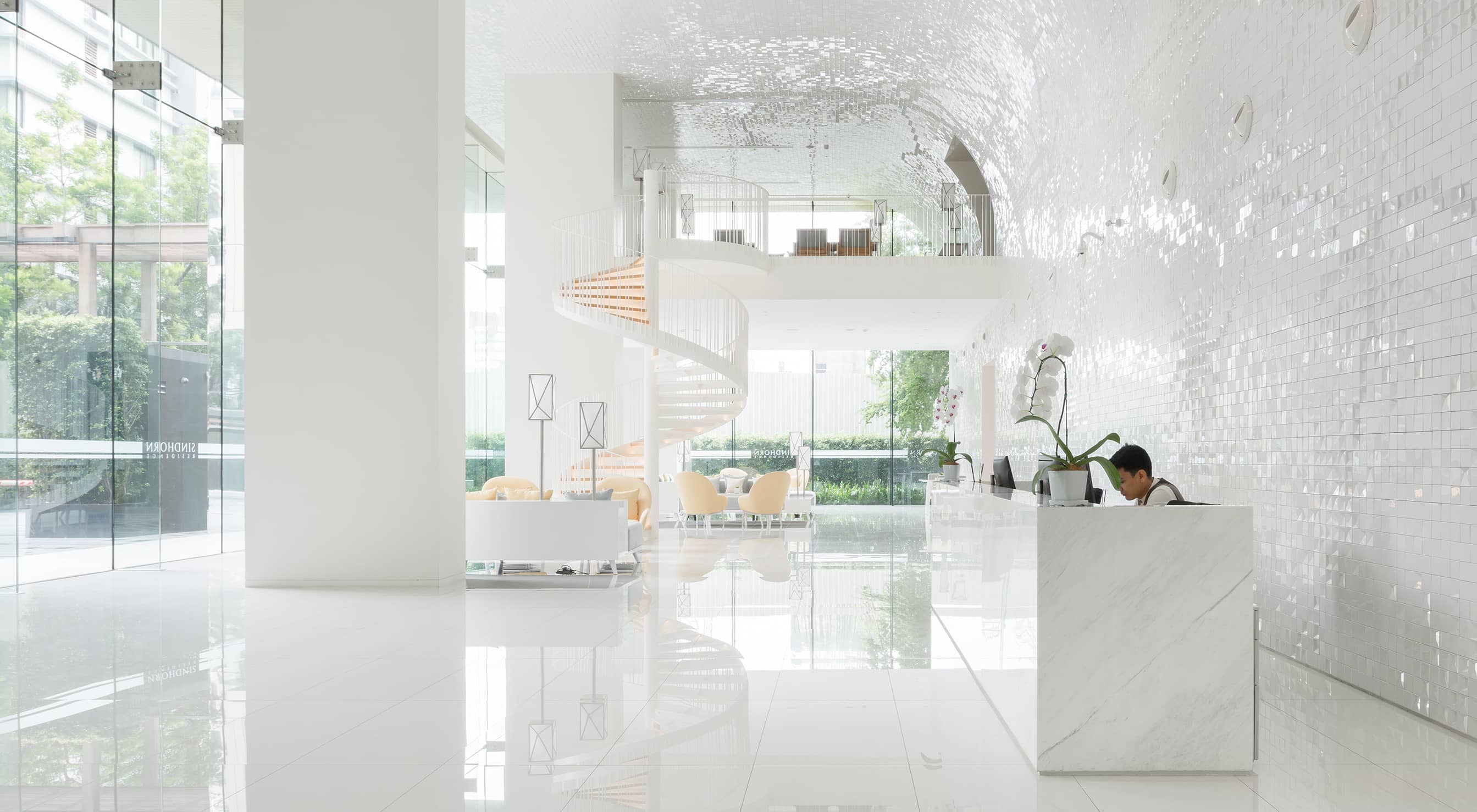 Sindhorn Residence white lobby with reception desk and spiral staircase