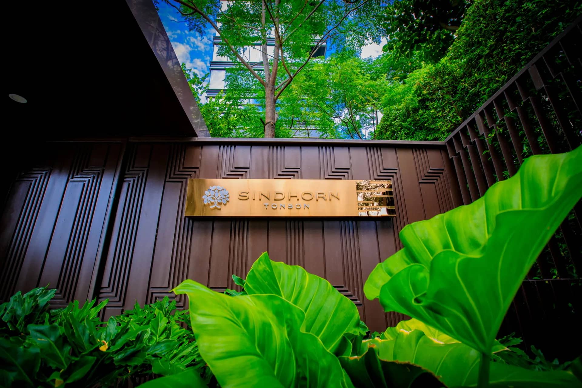 Sindhorn Tonson entrance sign surrounded by tropical plants