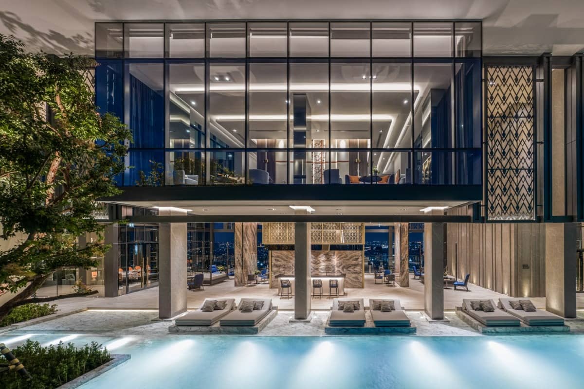 The Address Siam pool under glass pavilion at night with loungers