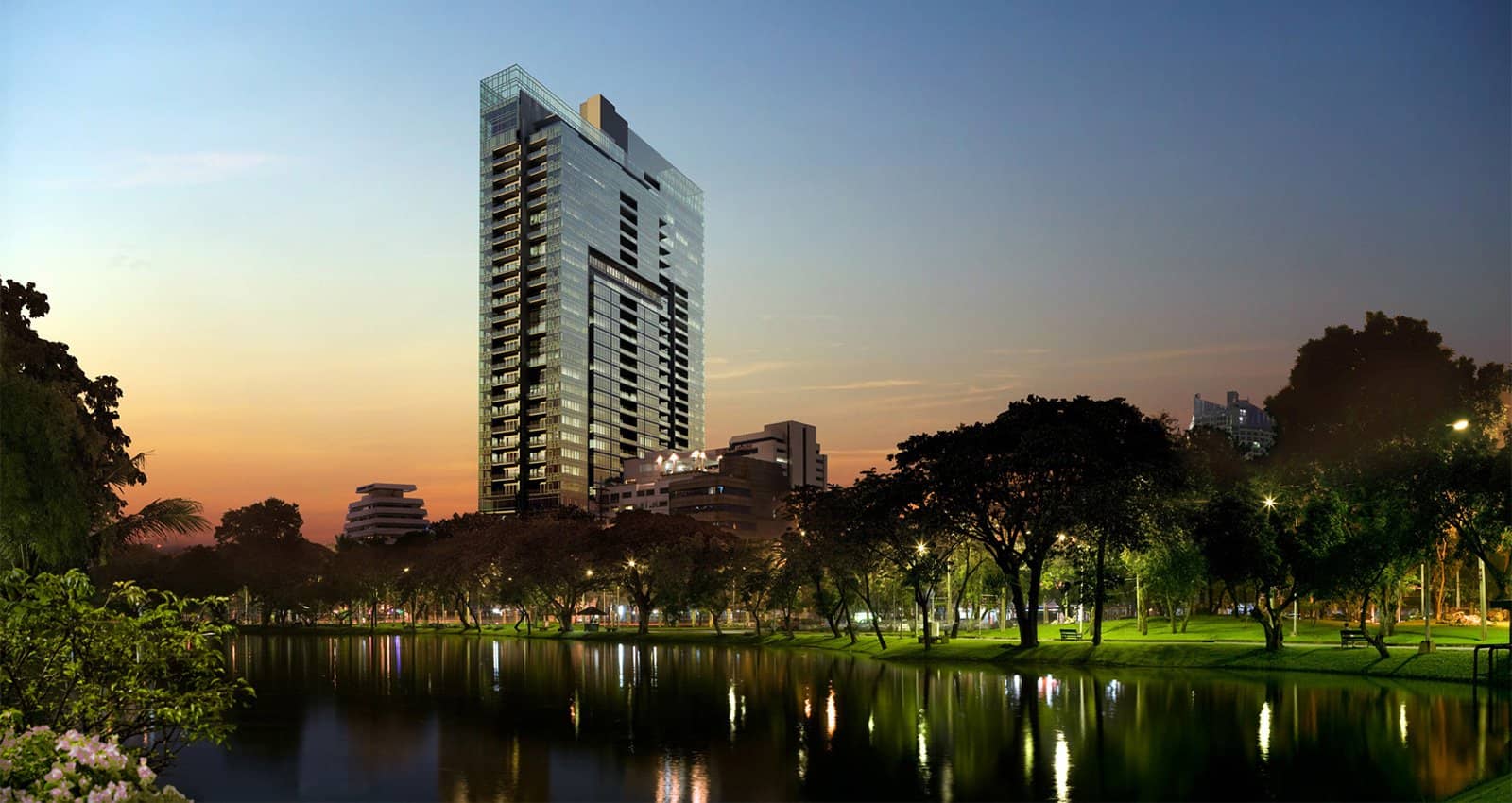 185 Rajadamri tower at sunset over a park lake