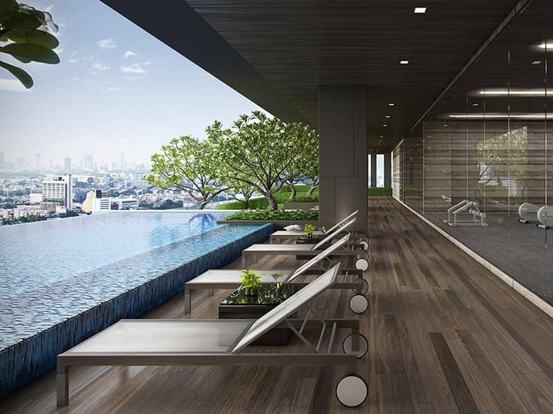The Lofts Ekkamai rooftop infinity pool with lounge chairs on a wooden deck, gym visible behind glass