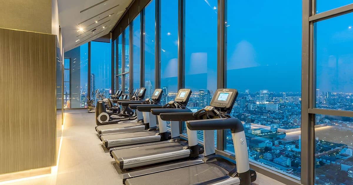 The Diplomat Sathorn fitness room with treadmills facing the city