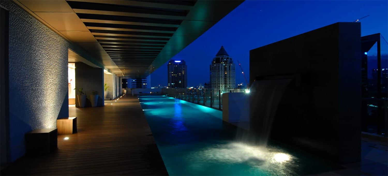The Legend Saladaeng rooftop pool deck and water wall at night