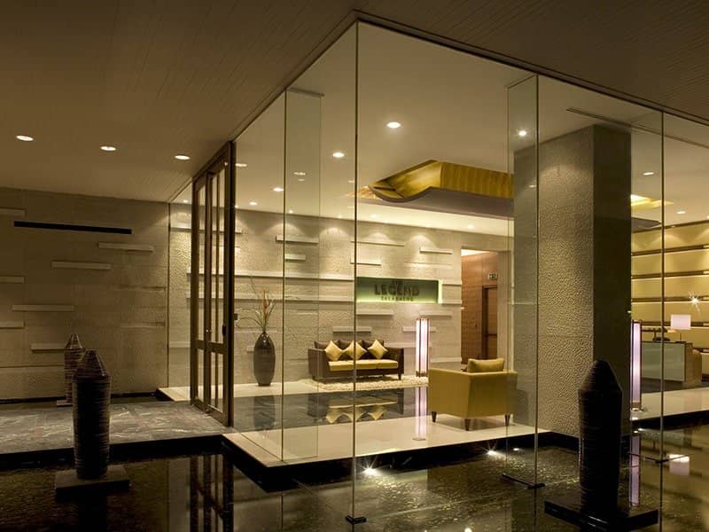 The Legend Saladaeng indoor lounge with glass walls, dark polished floor and warm lighting