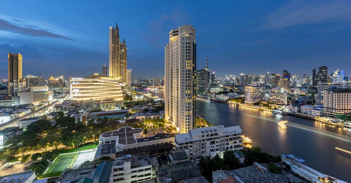 The River Condominium riverside tower at dusk beside the Chao Phraya River