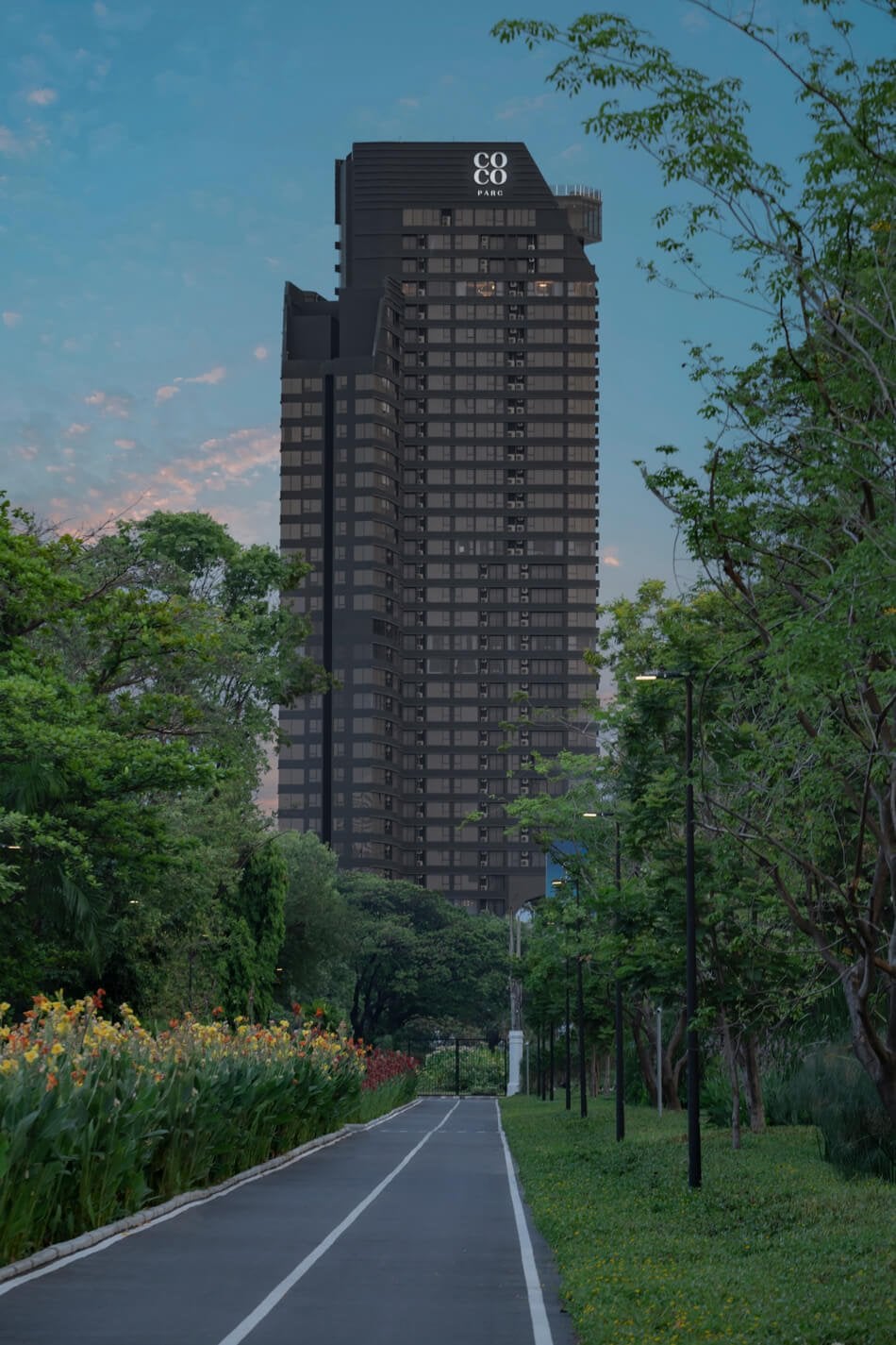 COCO Parc tower seen from the road at dusk with tree-lined street