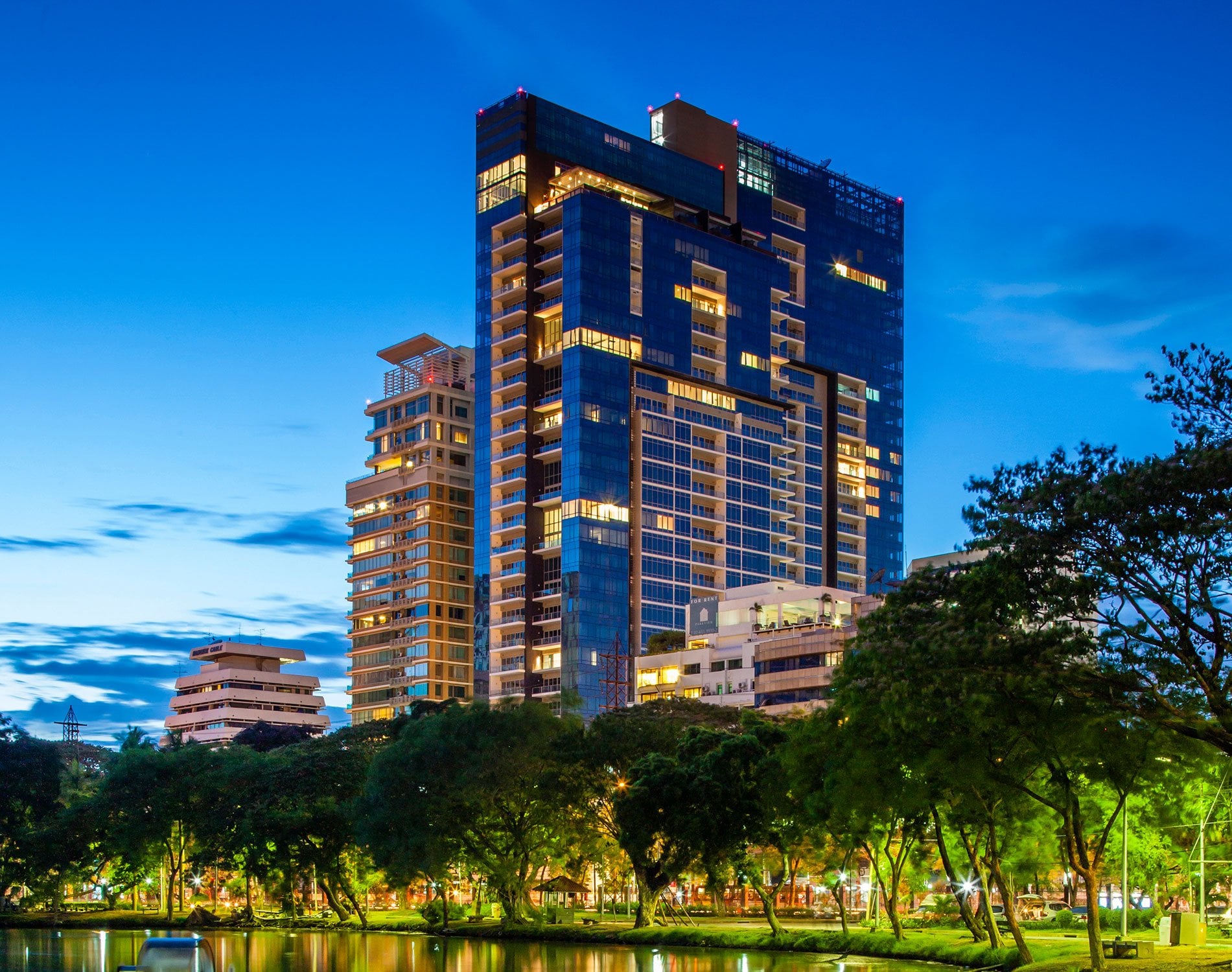 185 Rajadamri tower at dusk seen across greenery