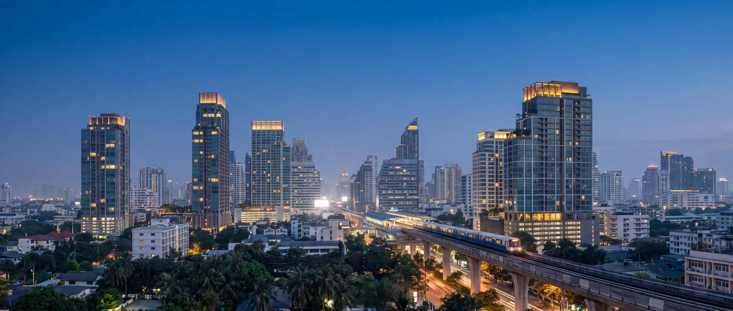 Sukhumvit condominium towers at dusk with the BTS Skytrain